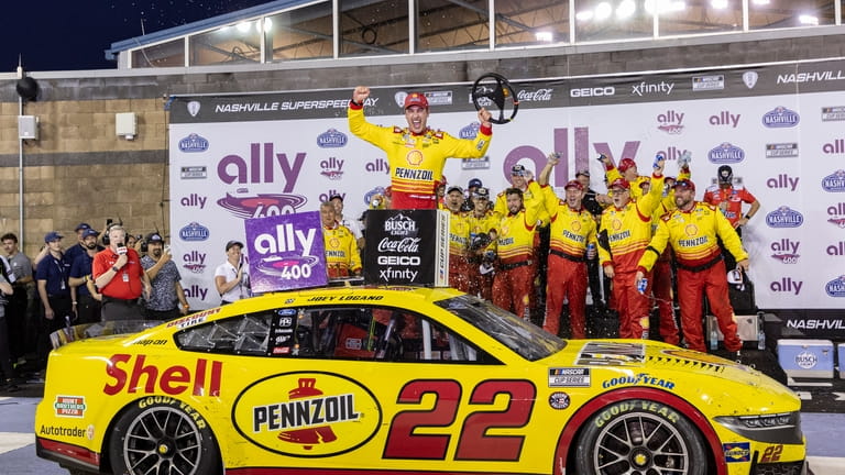 Joey Logano , top,celebrates after winning a NASCAR Cup Series...