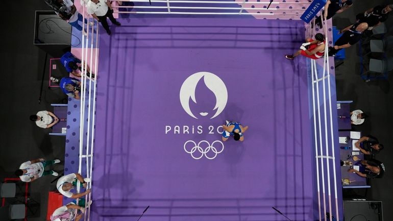 Italy's Angela Carini, center, reacts after she abandoned her fight...