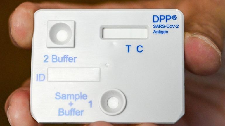 A lab technician holds one of  the COVID-19 antigen tests...