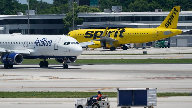 A JetBlue Airways Airbus A320, left, passes a Spirit Airlines...