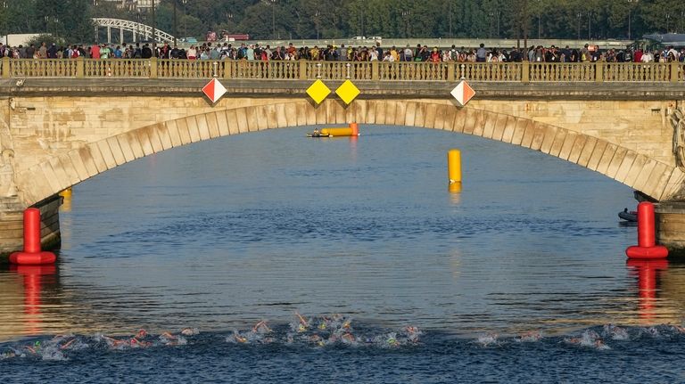 Athletes swim in the Seine river on the first leg...