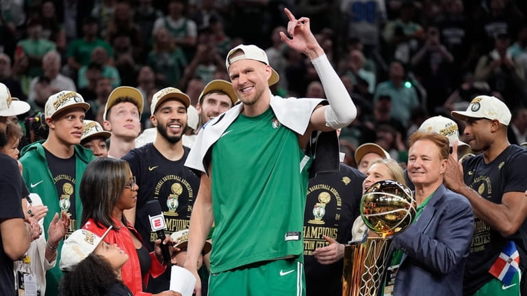 Boston Celtics center Kristaps Porzingis, center, raises his arm as...