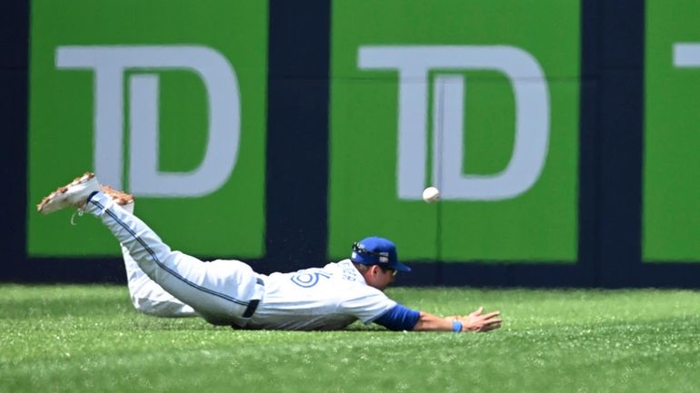 Toronto Blue Jays' Davis Schneider can't make a catch on...