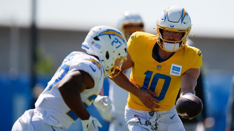 Los Angeles Chargers quarterback Justin Herbert, right, hands off to...