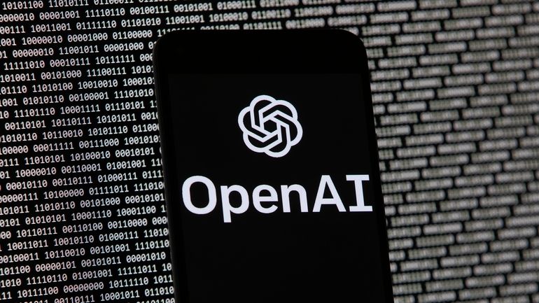 The OpenAI logo appears on a mobile phone in front...