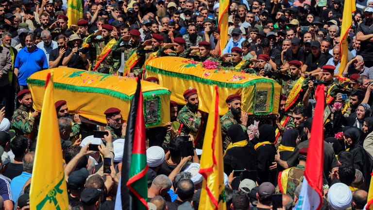 Mourners carry the coffins of Hezbollah fighters Mohammed Hussein Qassem...