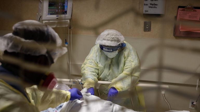 Medical staff assist a COVID-positive patient who was crying out...