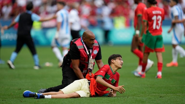 A steward catches a pitch invader during the men's Group...