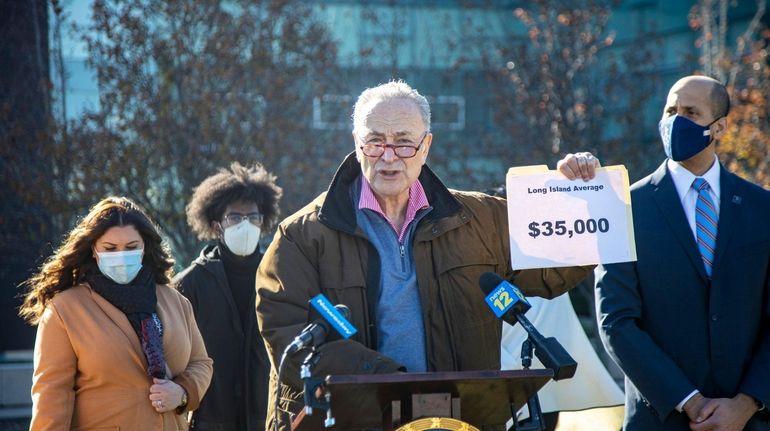 Senator Charles Schumer holds a sign at a news conference...