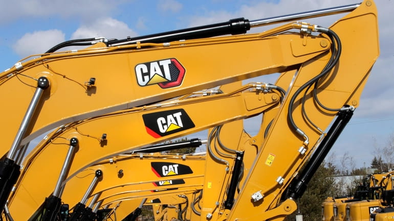 Excavator booms, adorned with the Caterpillar Inc. "CAT" logo, are...