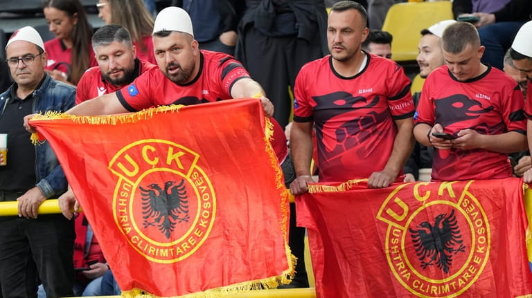 Albanian supporters hold flags of the Kosovo Liberation Army, also...