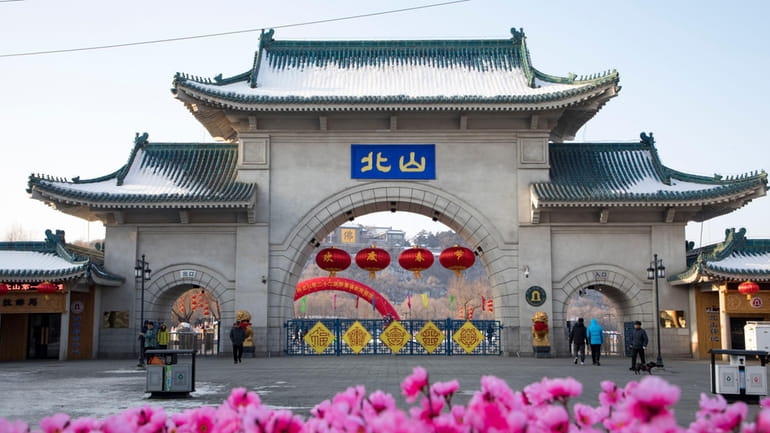 Tourists walk past a gateway with the name "Beishan" seen...