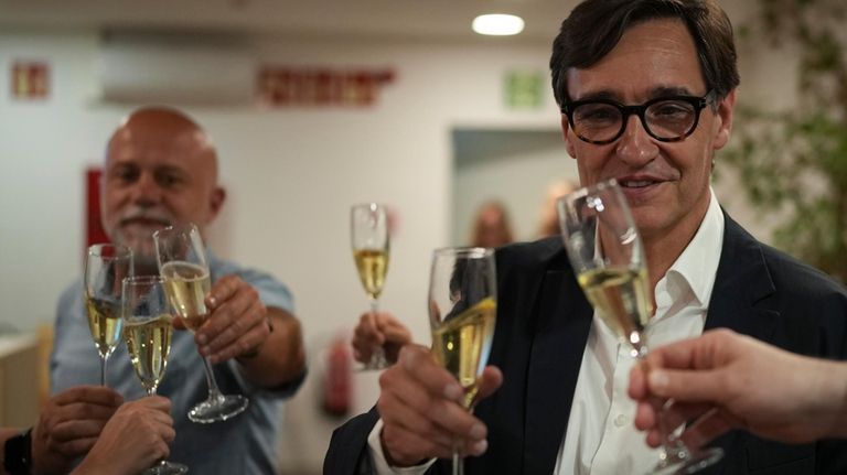 Socialist candidate Salvador Illa makes a toast with members of...