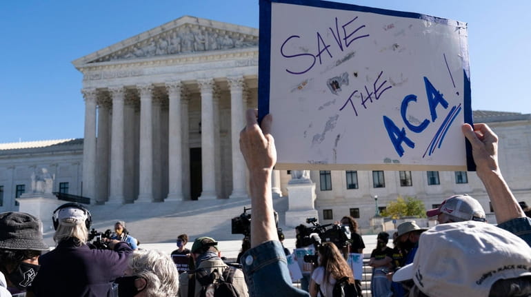 A demonstrator holds a sign in front of the Supreme Court...