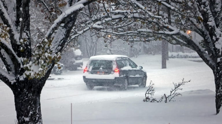 A car drives through the snow on E. Orange St....