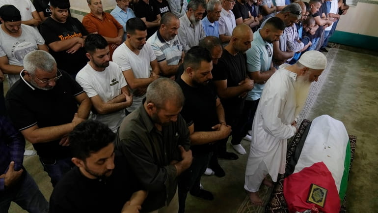Palestinian mourners pray at the body of Mohammad Hoshiya, 12,...