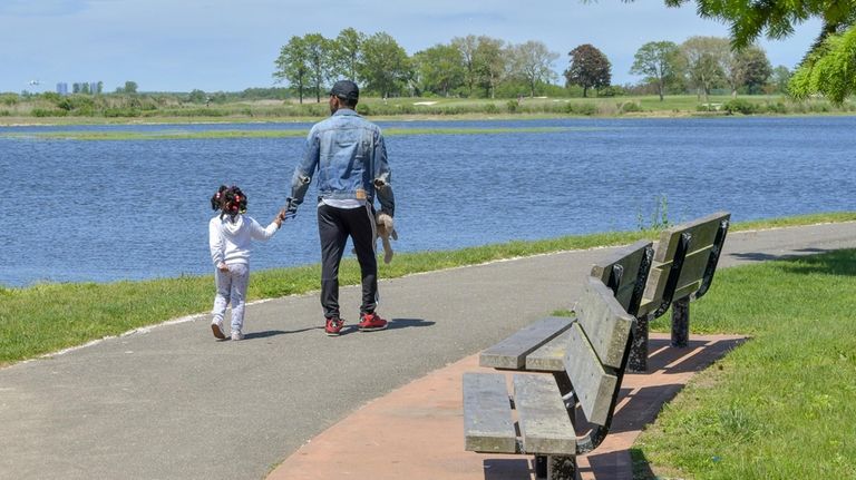 A family walks along the shoreline in Inwood.