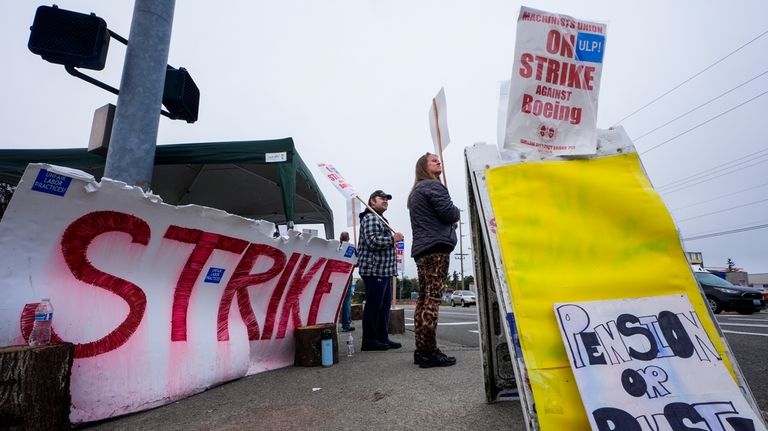 Denise Strike, a 13-year employee of Boeing, right, waves picket...