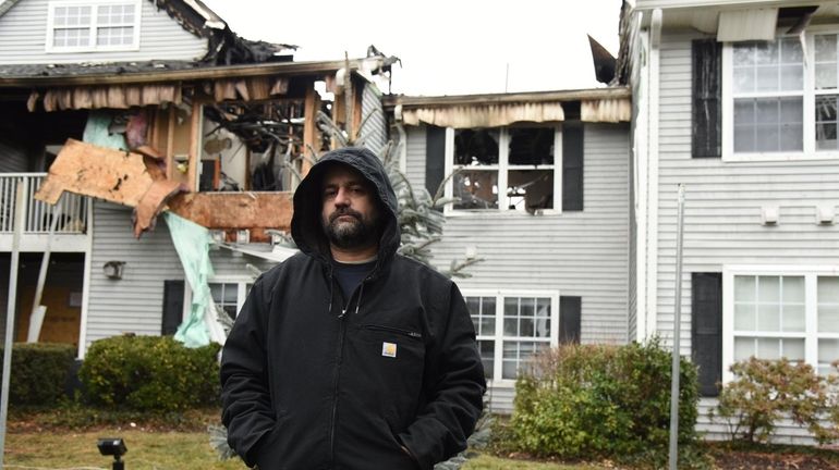 Anthony Wilson stands in front of the remains of his...