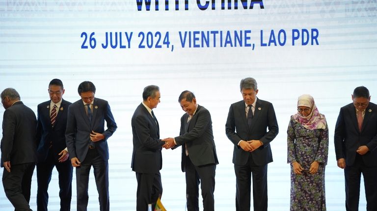 Chinese Foreign Minister Wang Yi, 4th from left, shakes hands...