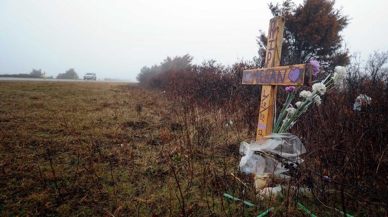 A car passes by a makeshift memorial for a victim...