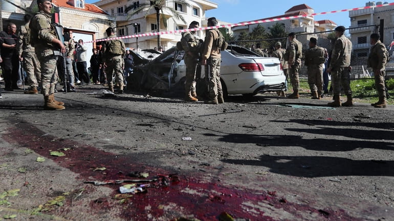 Lebanese army soldiers gather around a damaged car near the...