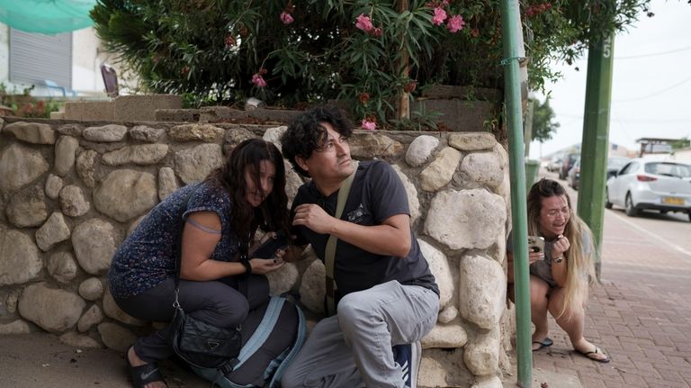 Israelis take cover from the incoming rocket fire from the...