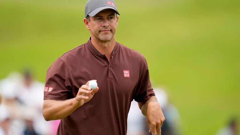 Adam Scott, of Australia, waves after making a putt on...