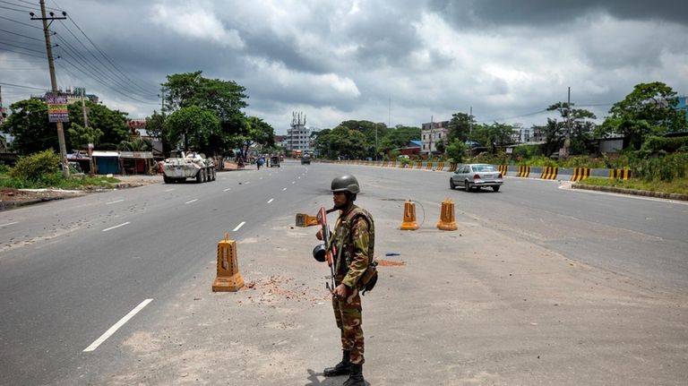 A military person stands guard on a highway on the...