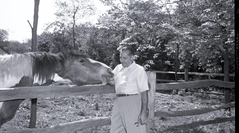 Mobster Frank Costello pets a horse on the grounds of...