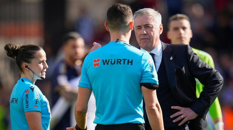 Real Madrid's head coach Carlo Ancelotti, right, talks with referee...