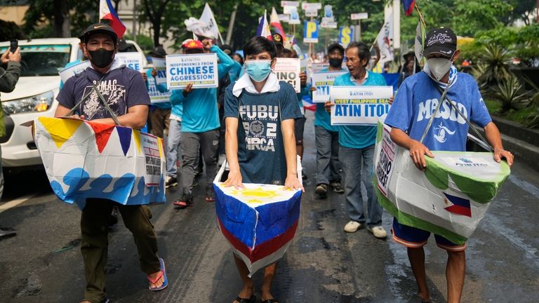 Filipino fishermen and activists wear boat costumes to protest against...