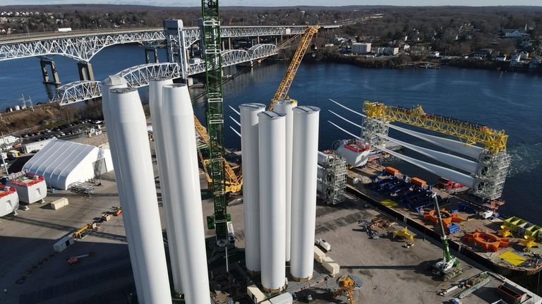 While wind farm towers, left, stand on the ground, a...