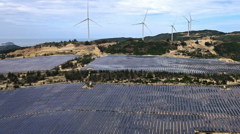 Solar panels work near wind turbines in Quy Non, Vietnam,...