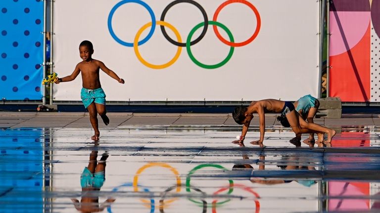 Children play at a splash fountain area near signage for...