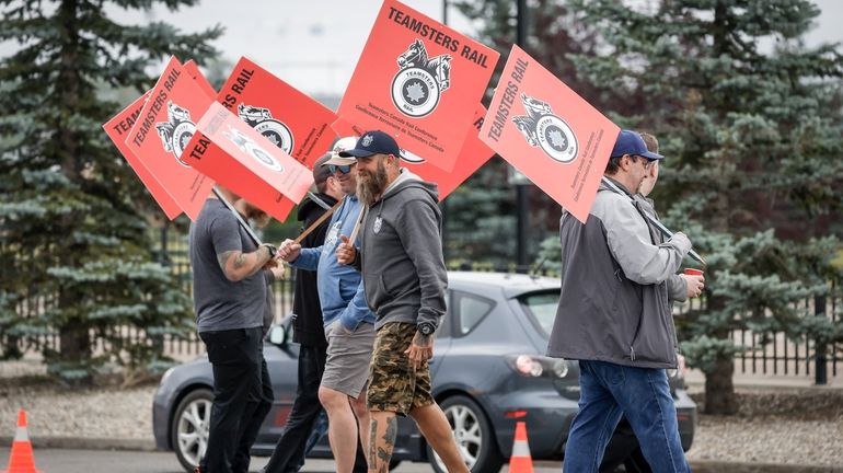 Teamsters Canada Rail Conference members walk a picket line at...