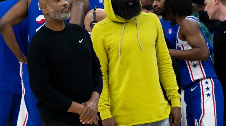 Philadelphia 76ers' James Harden, right, looks on with assistant coach...