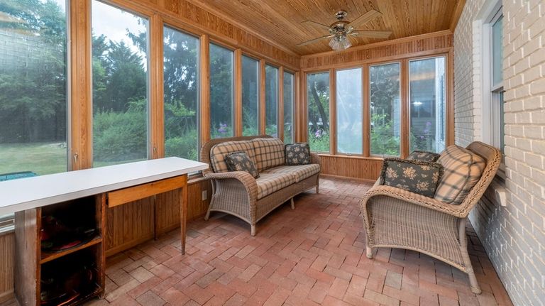 A wood-paneled enclosed porch with red-brick flooring overlook the grounds.