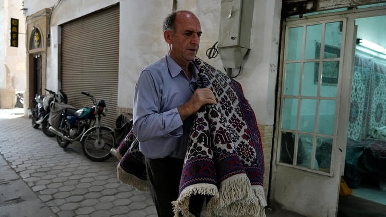 An Iranian man carries a carpet at the traditional bazaar...