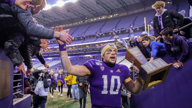 Washington quarterback Jacob Eason high fives fans as he leaves...