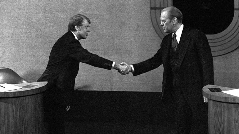 Jimmy Carter, left, and Gerald Ford, right, shake hands before...