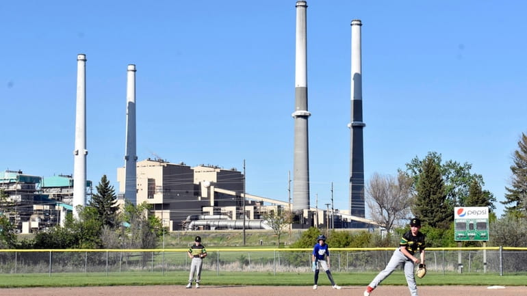 The coal-fired Colstrip Generating Station is seen behind youths playing...