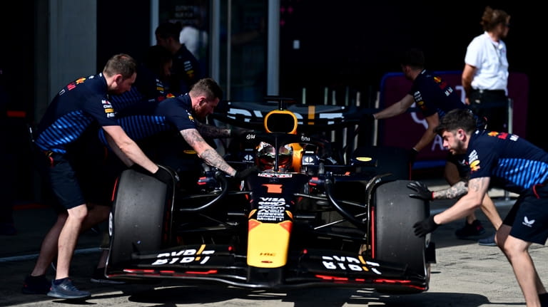 Red Bull mechanics handle the car of Max Verstappen, of...