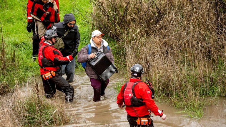 Search and rescue workers evacuate men from a homeless encampment...