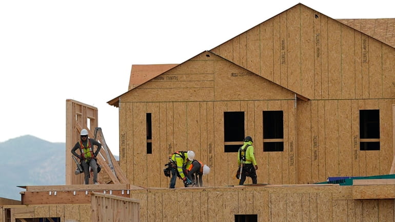 Workers construct new homes in a development on Tuesday, June...