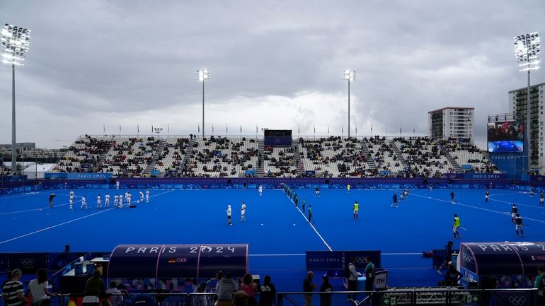 Players from Germany, left, and France field hockey teams warmup...