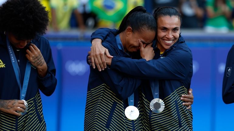 Brazil's Marta, right, consoles a teammate during the medal ceremony...