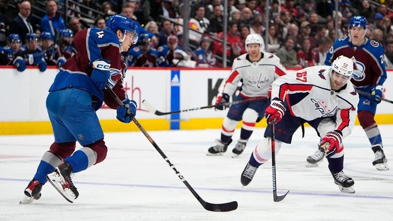 Colorado Avalanche defenseman Bowen Byram, left, looks to shoot the...