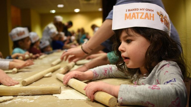 Skylar Levey, 3, of Greenlawn, makes matzo during an interactive...