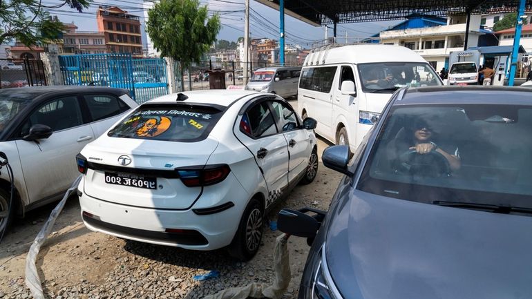 A man sits waits in his electric car while recharging...